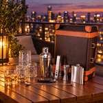 Brown leatherette bar set with 4 whiskey glasses on a balcony at dusk