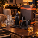 Leatherette bar set with black matte tools and 4 whiskey glasses in a living room at night